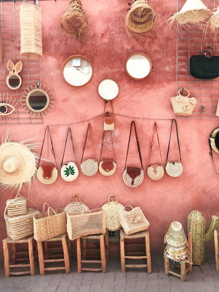 photo of wicker bags and straw hats on a pink wall